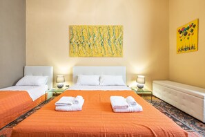 A hotel room with two beds, a large painting, and a bench.