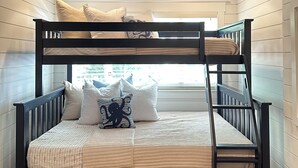 Un lit superposé avec un ventilateur de plafond, des murs en bois et une fenêtre donnant sur un paysage agréable.