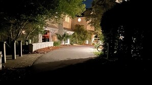 Une rue résidentielle la nuit, avec des maisons des deux côtés, un trottoir et un lampadaire.