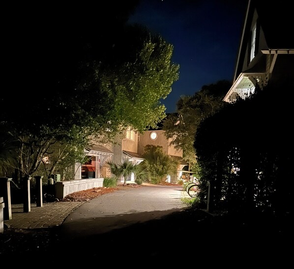 A residential street at night with houses on both sides, a sidewalk, and a street lamp. - Welcome to Shell Cottage on Bald Head Island! (Bald Head Island)