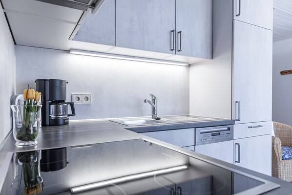 Une cuisine moderne équipée d’appareils électroménagers en acier inoxydable, d’un évier encastré et d’une machine à café.