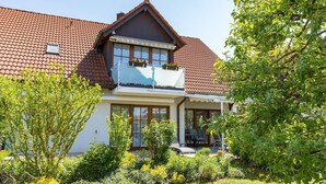 Een tweelaags huis met een balkon, grote ramen en een tuin.