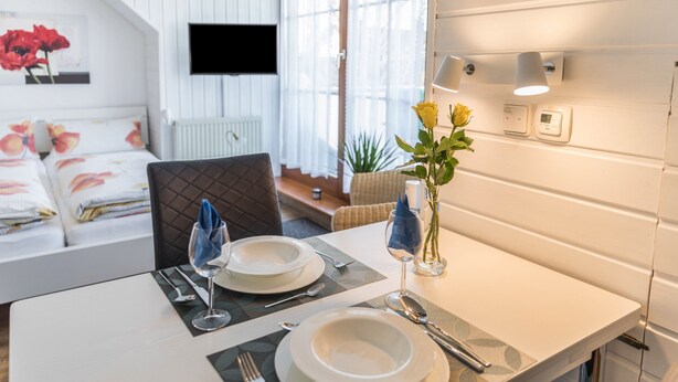 Een eettafel gedekt met borden, bestek en een vaas met bloemen.