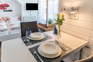 Une table à manger dressée avec des assiettes, des couverts et un vase rempli de fleurs.
