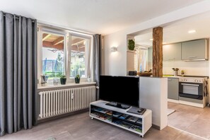 Un salon moderne doté d’un téléviseur à écran plat, d’une bibliothèque et offrant une vue sur l’extérieur par une fenêtre.