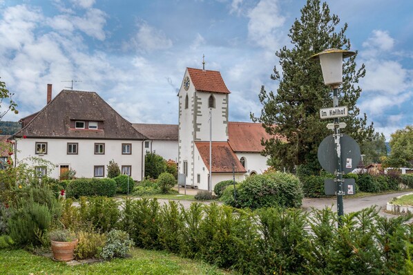 Un bâtiment blanc surmonté d’une tour horlogée, une enseigne indiquant « Im Kellhof » et un lampadaire.