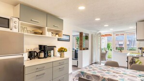 A modern kitchen with a built-in microwave, coffee maker, and shelves with kitchenware. - Schweizer Holiday Apartment – Relaxing Getaway at Lake Constance in Hemmenhofen (Gaienhofen)
