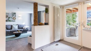 A modern living room with a sofa, coffee table, and a view through a glass door to an outdoor area. - Schweizer Holiday Apartment – Relaxing Getaway at Lake Constance in Hemmenhofen (Gaienhofen)