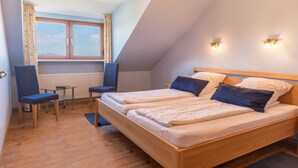 Una habitación con una cama, dos sillones, una mesita y una ventana con cortinas.