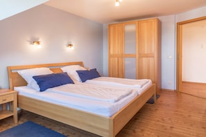 Un dormitorio con una cama de madera, dos mesitas de noche, un armario y luces en la pared.