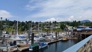 A marina with various boats docked, a wooden pier, and buildings in the background.