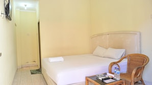 A small, simple room with a bed, a chair, a table, and a television. - Hotel King's (Wates)
