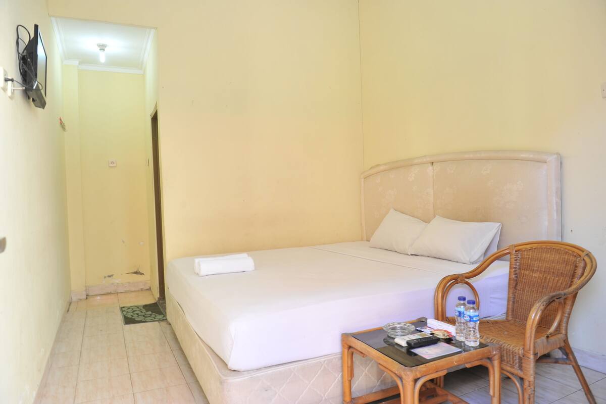 Una habitación pequeña y sencilla con cama, una silla, una mesa y televisor.