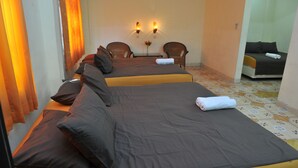 A hotel room with two beds, a small table, two chairs, and a vase with flowers. - Hotel King's (Wates)