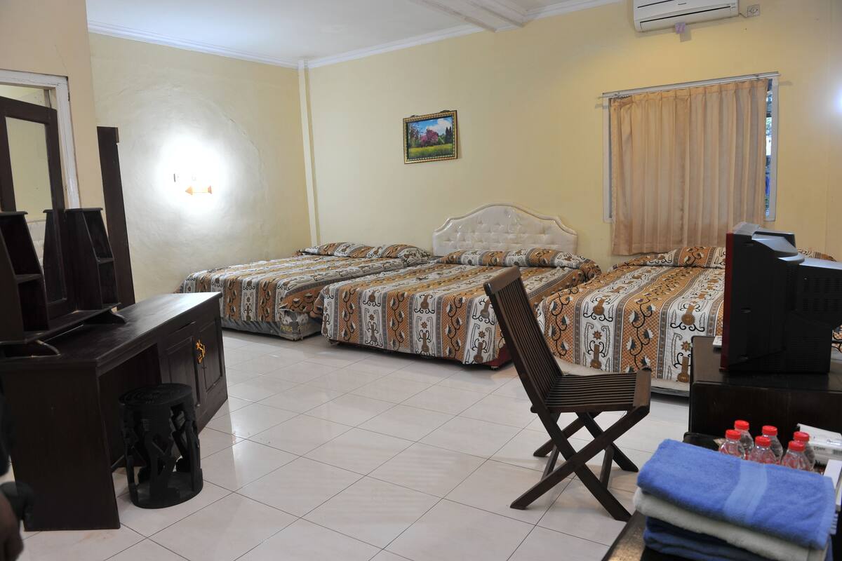 A hotel room with two beds, a desk with a computer, a chair, and a TV.