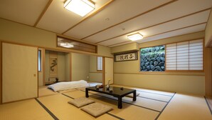 A traditional Japanese room with tatami flooring, a low table, cushions, and a sliding door. - Temple Hotel Takeibo (Minobu)