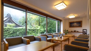 A hotel room with large windows, wooden furniture, and a traditional Japanese temple view. - Temple Hotel Takeibo (Minobu)