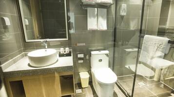 Un baño moderno con cabina de ducha de vidrio, un lavabo con espejo y un inodoro.