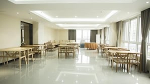 A spacious hotel room with a large dining area, multiple tables, and chairs.