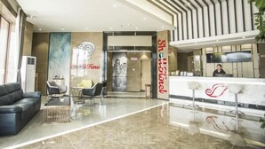 A hotel lobby with a reception desk, seating area, and a large mirror.