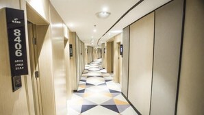 A hotel hallway with a geometric patterned floor, doors numbered 8406, and a modern design.
