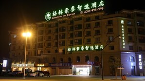 Ein Hotel mit auffälliger Beschilderung für GreenTree Inn Express, mit einem Baum-Logo und Kontaktdaten.