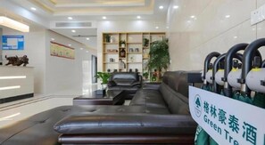 A hotel lobby with a reception desk, seating area, and a sign indicating a green initiative. - Greentree Inn Jiaxin Puyuan Kaixuan Road (Jiaxing)