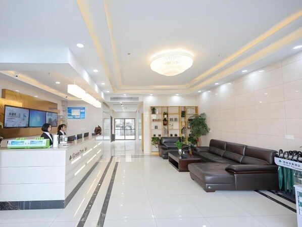 A hotel lobby with a reception desk, seating area, and a chandelier.
