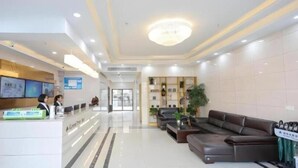 Eine moderne Hotellobby mit Empfangsschalter, Sitzbereich und einer großen Kronleuchter.