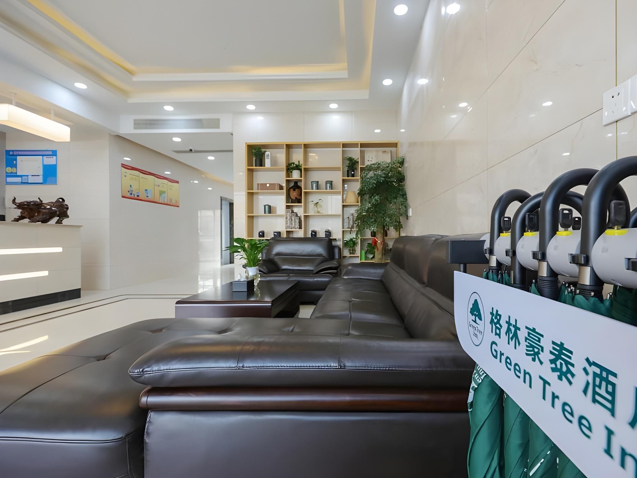 A reception area with a black leather sofa, a reception desk, and a sign indicating a Green Tree Inn.