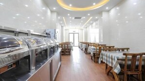 Eine Cafeteria mit Edelstahl-Speisenausgabesystemen, Holztischen mit karierten Tischdecken und einem Fliesenboden.