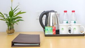 Ein Schreibtisch mit einem braunen Notizbuch, einem Edelstahlkocher, zwei weißen Tassen mit grünen Logos und zwei Wasserflaschen.
