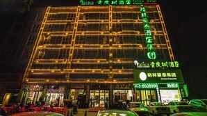 Um hotel com um letreiro verde grande para 'Vatica Hotel' e o logotipo verde da 'GreenTree Inn'.