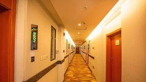 A hotel hallway with numbered doors, a patterned carpet, and a long corridor. - Vatica Jieshou City New Passenger Transport Center Hotel (Fuyang)