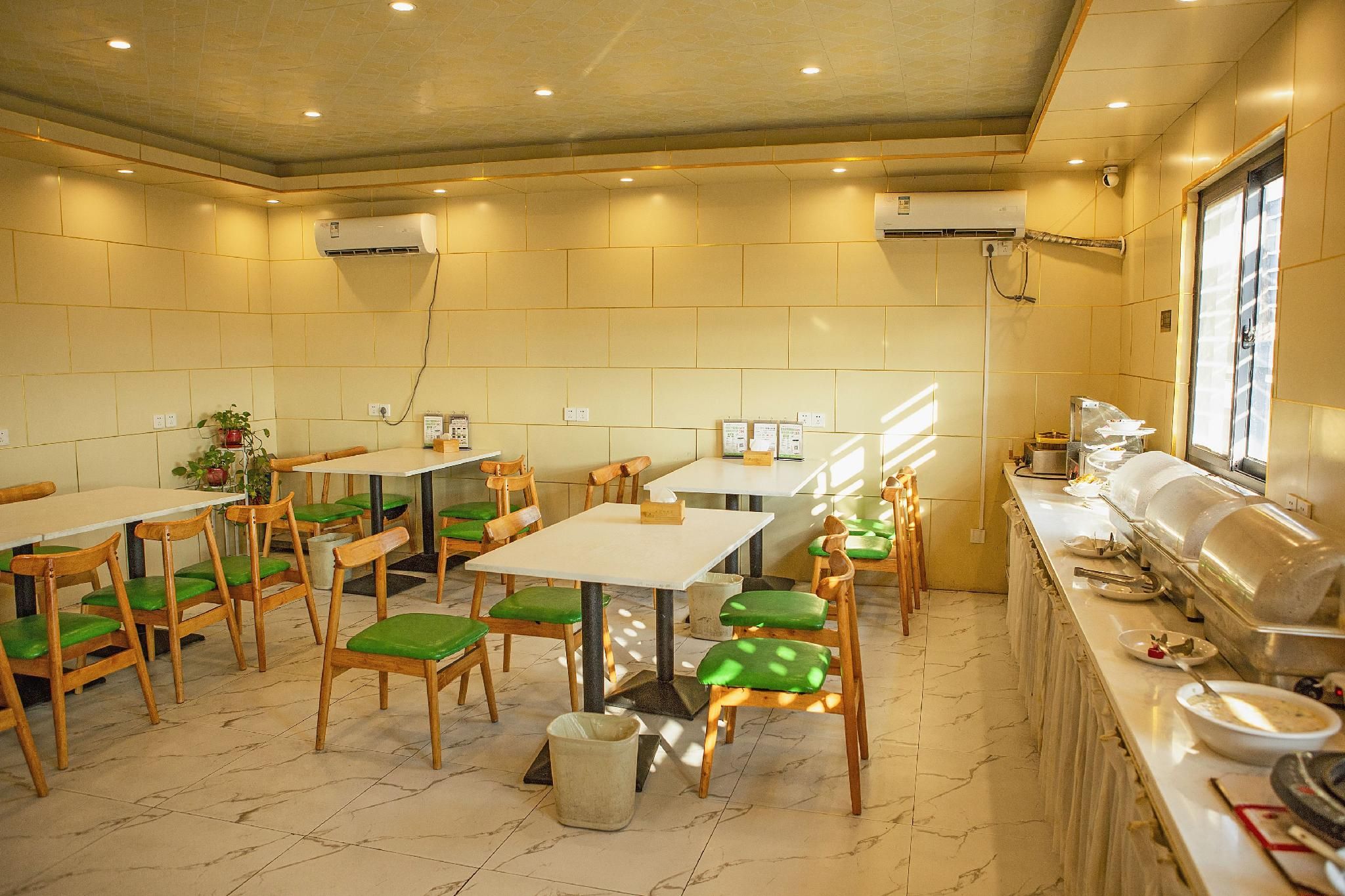 A dining area with tables and chairs, a buffet line, and a window with blinds.