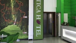 A hotel reception area with a green reception desk, a chandelier, and a wall with a map and the hotel name. - Vatica Jieshou City New Passenger Transport Center Hotel (Fuyang)