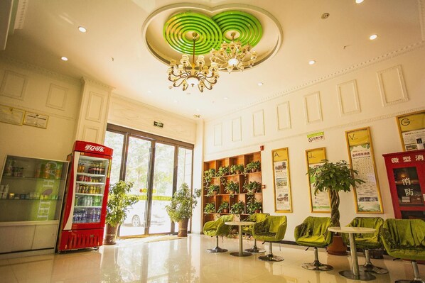 A lobby with a vending machine, green chairs, a chandelier, and a plant. - Vatica Jieshou City New Passenger Transport Center Hotel (Fuyang)