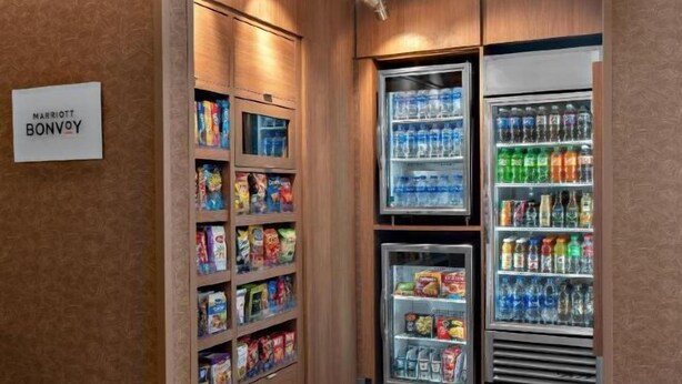 Et hotelpantry med hylder fyldt med snacks og drikkevarer.