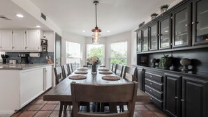 A spacious kitchen with a long dining table, dark cabinetry, and a hanging light fixture. - 3Kingbeds/Fireplace/Deck/6 Flags/Airport (Grand Prairie)