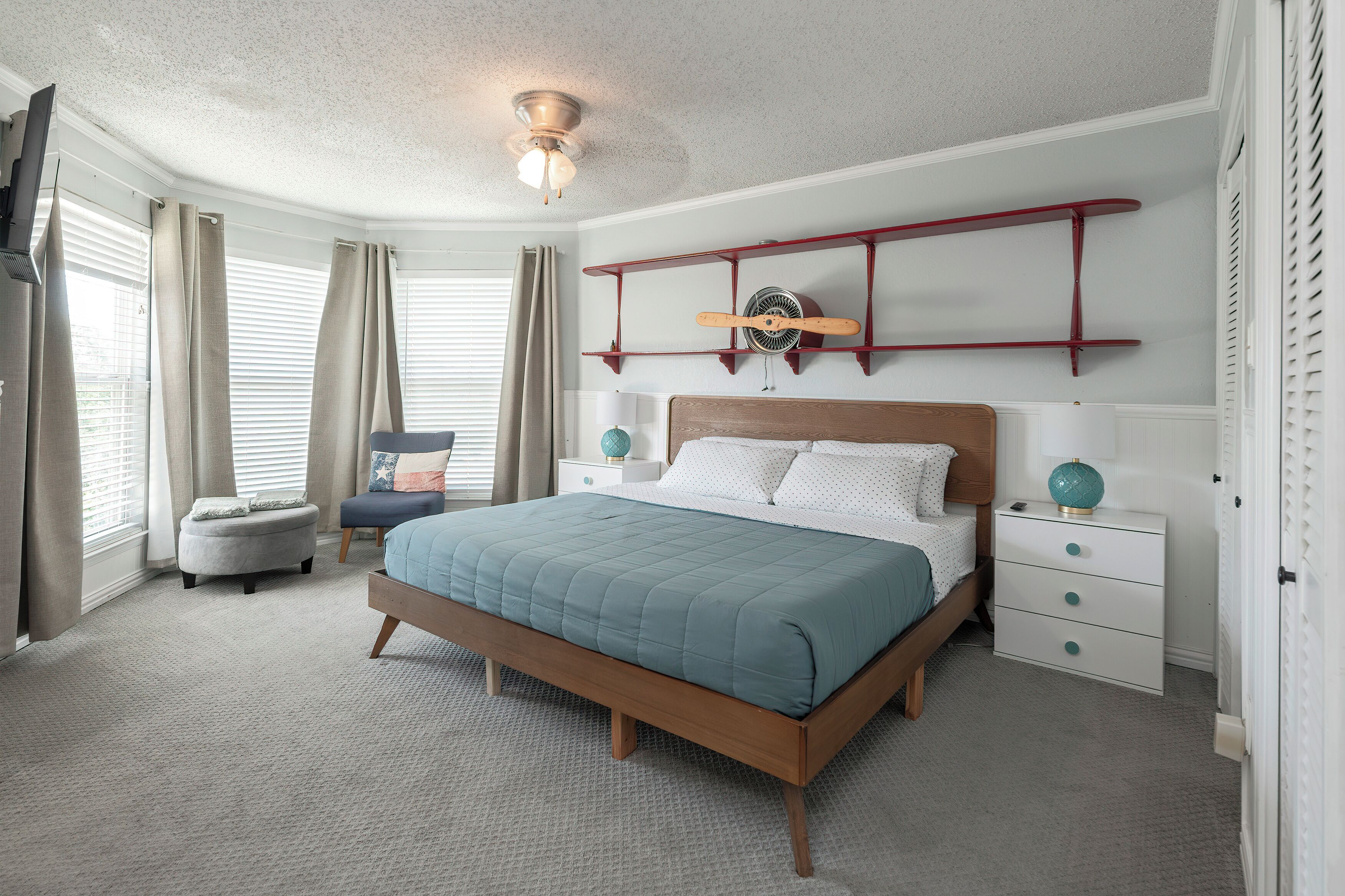 A bedroom with a bed, bedside tables, a ceiling fan, and a window with curtains.