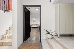A hallway with a black door, a staircase, a white potted plant, and a light-colored wardrobe.
