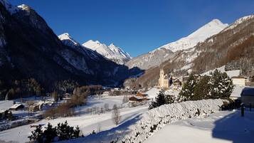 Un paysage montagneux enneigé, avec une église et des bâtiments dans la vallée.
