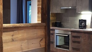 A modern kitchen with wooden accents, a built-in oven, and a large window.