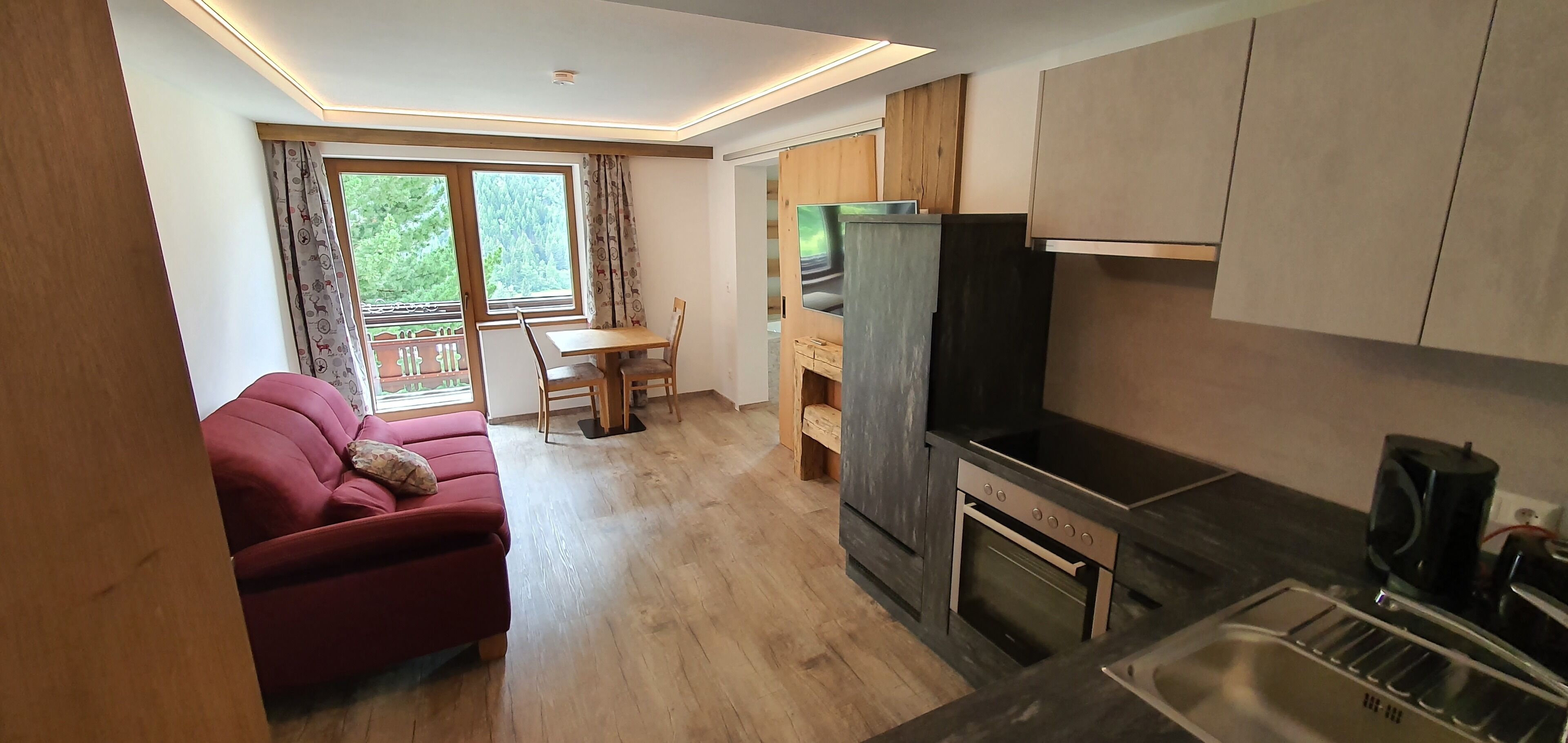 A compact living space with a kitchenette, a dining area, and a sofa.