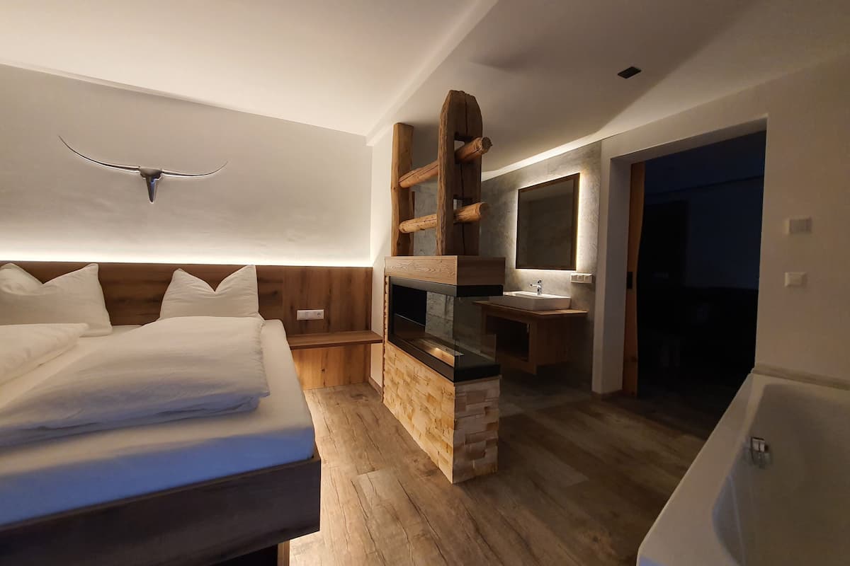 A modern bedroom with a wooden headboard, a built-in TV, a bedside table, and a large bed.