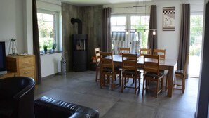 Een moderne woonkamer met een open haard, een eettafel en zachte zithoek.