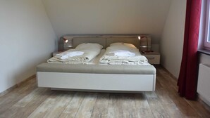 Een slaapkamer met een bed, twee nachtkastjes en een raam met gordijnen.