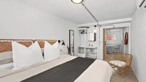 Een slaapkamer met een bed, een stoel, een bureau en een kledingkast.