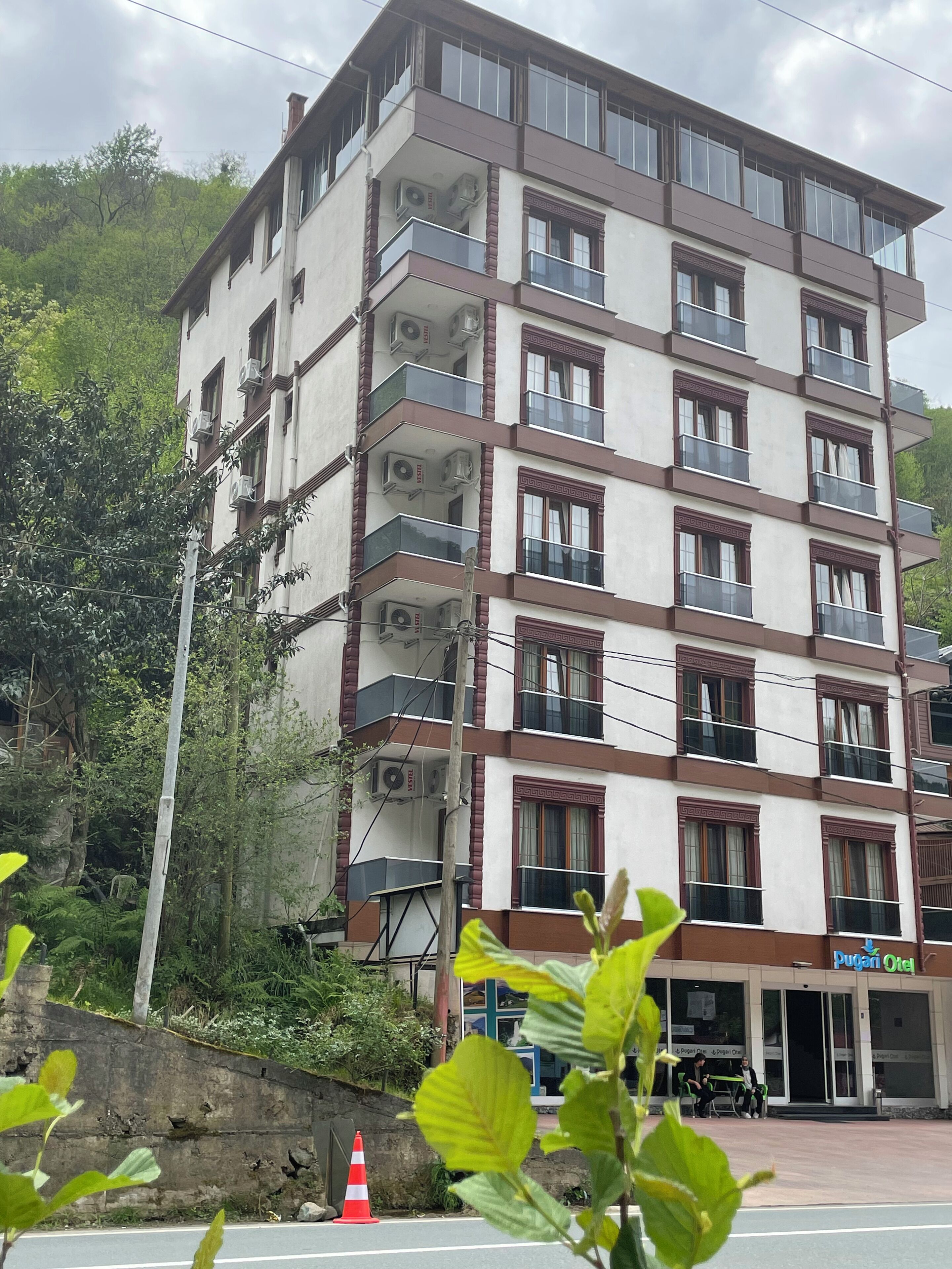 Um hotel com vários andares, varandas, aparelhos de ar condicionado e uma placa com a inscrição 