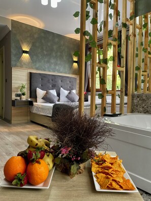 A bedroom with a bed, bedside tables, and a nightstand. There is a decorative plant and a fruit platter on the table. - Puğari Otel (Ardesen)